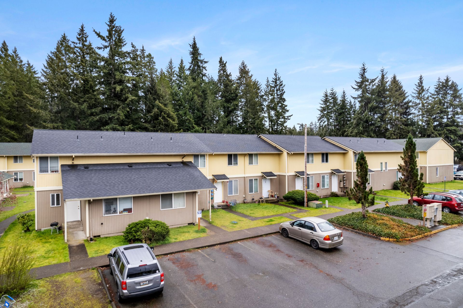 A row of houses with cars parked in front of them.