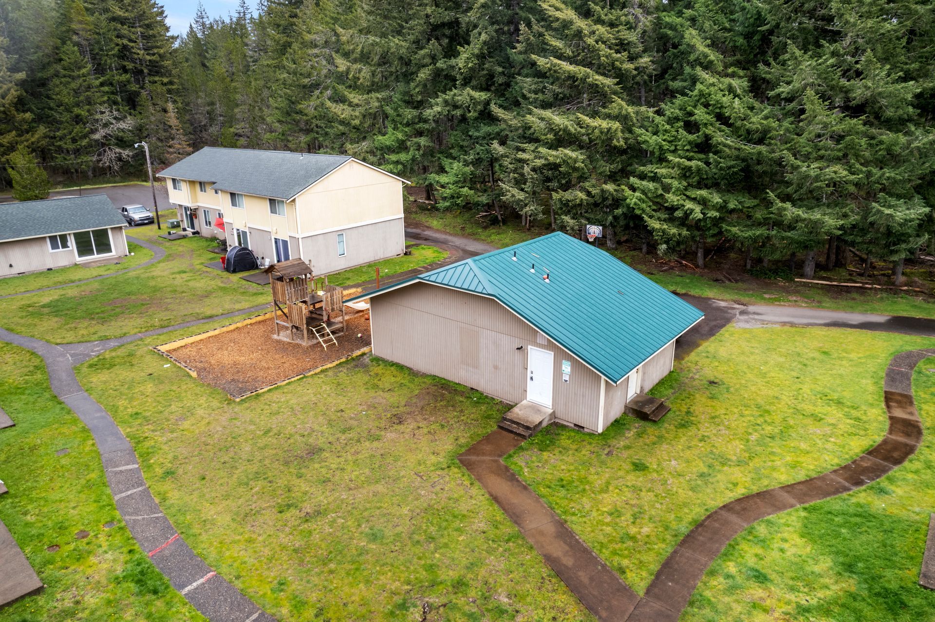 An aerial view of a house with a green roof surrounded by trees.
