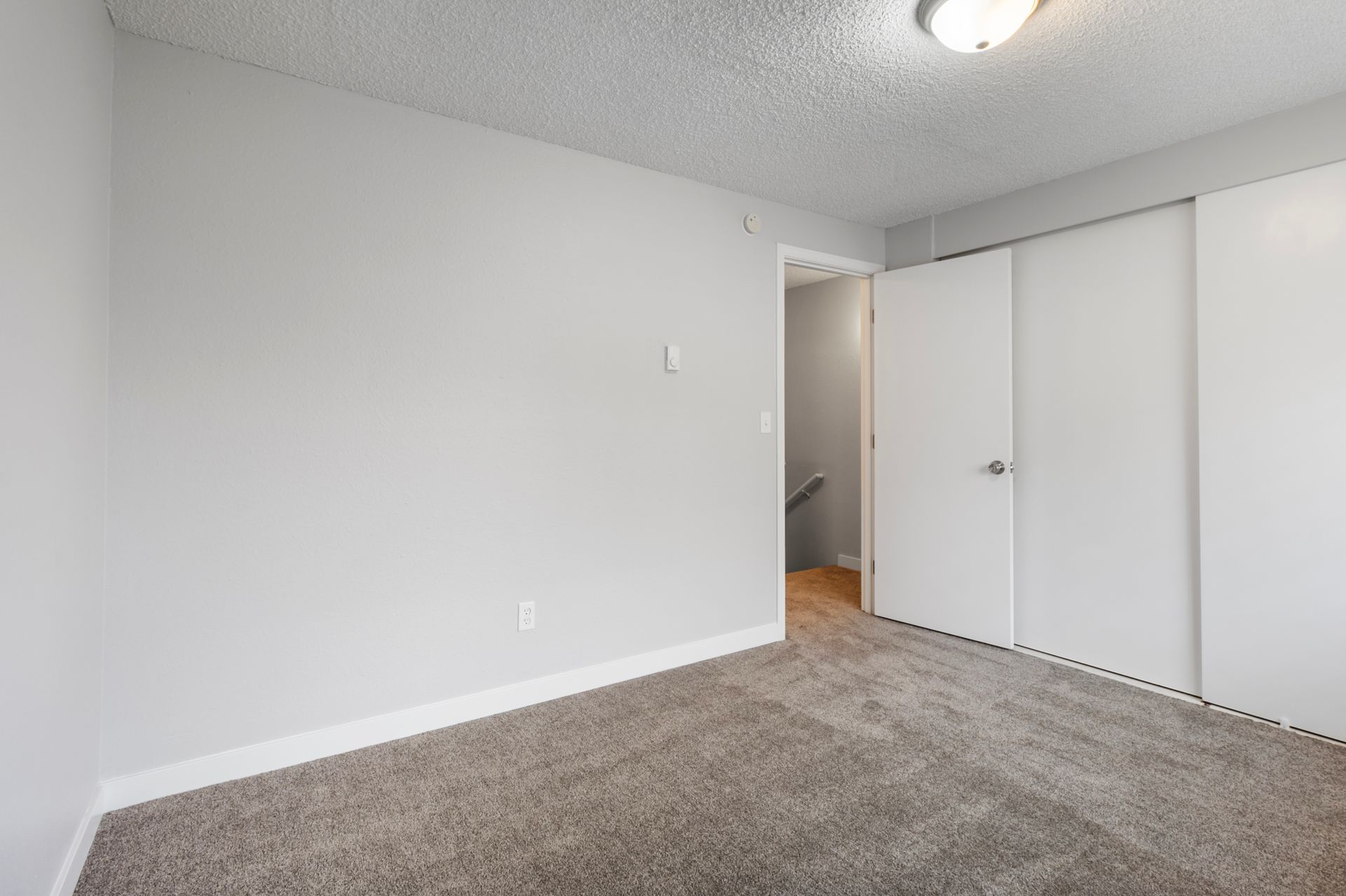 An empty bedroom with a carpeted floor and white walls.