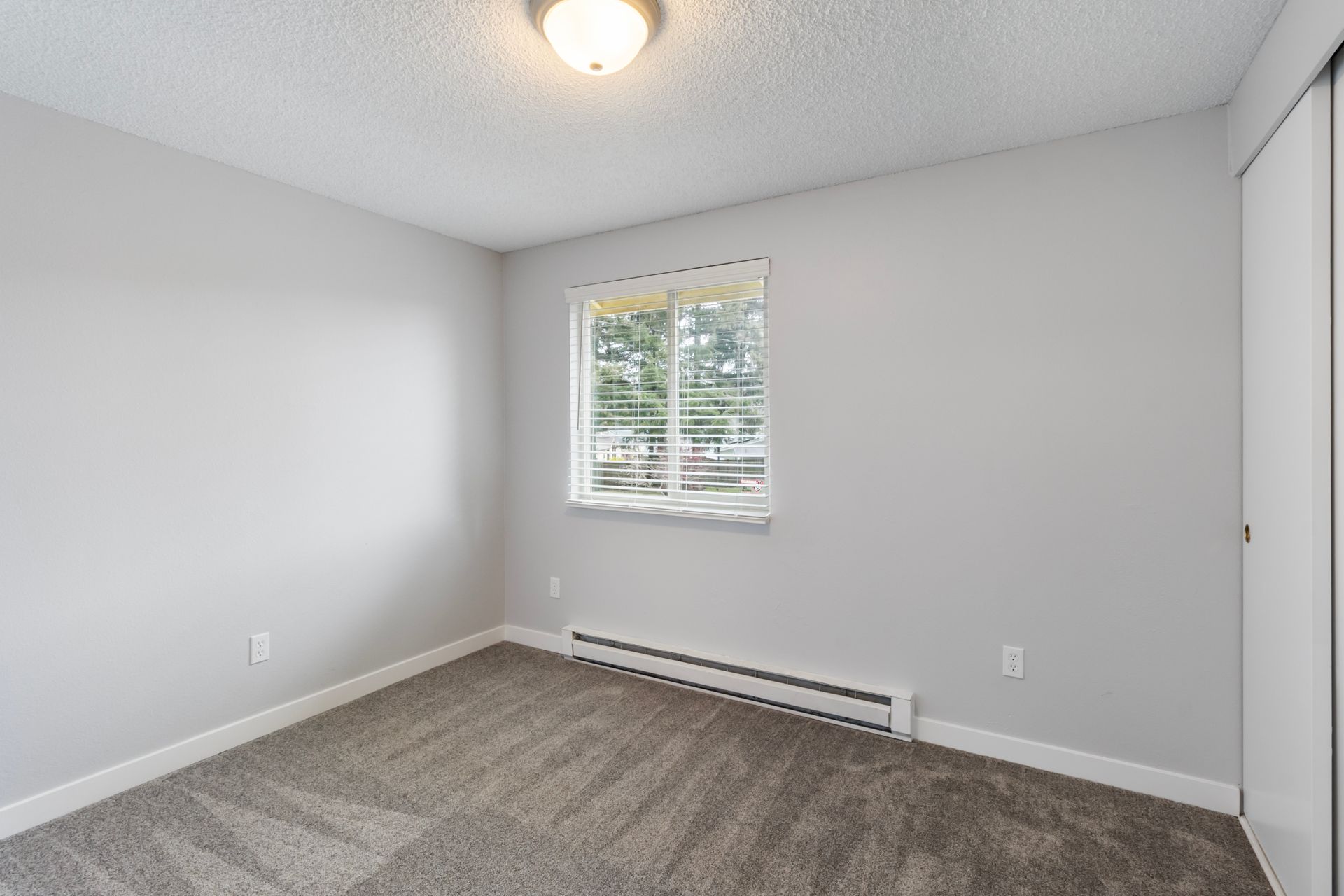 An empty bedroom with a window and a ceiling fan.