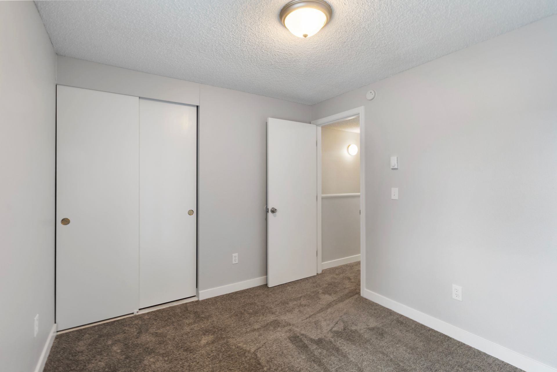 An empty bedroom with two closets and a carpeted floor.