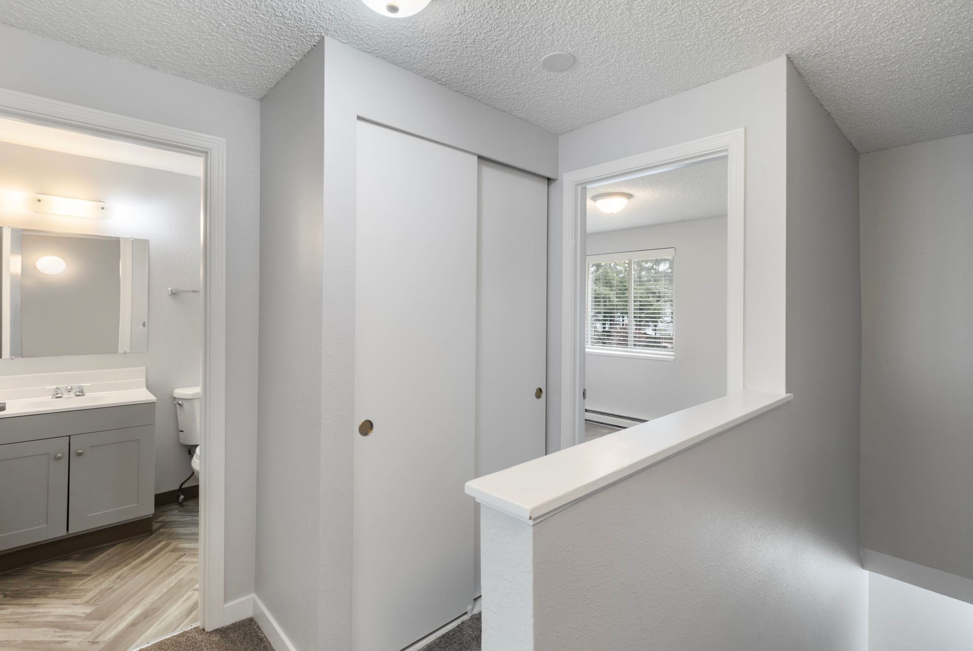 A hallway with sliding doors leading to a bathroom and a closet.