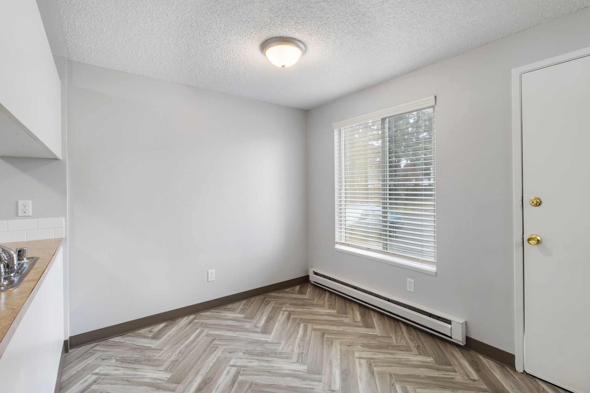 An empty room with a herringbone floor and a window.