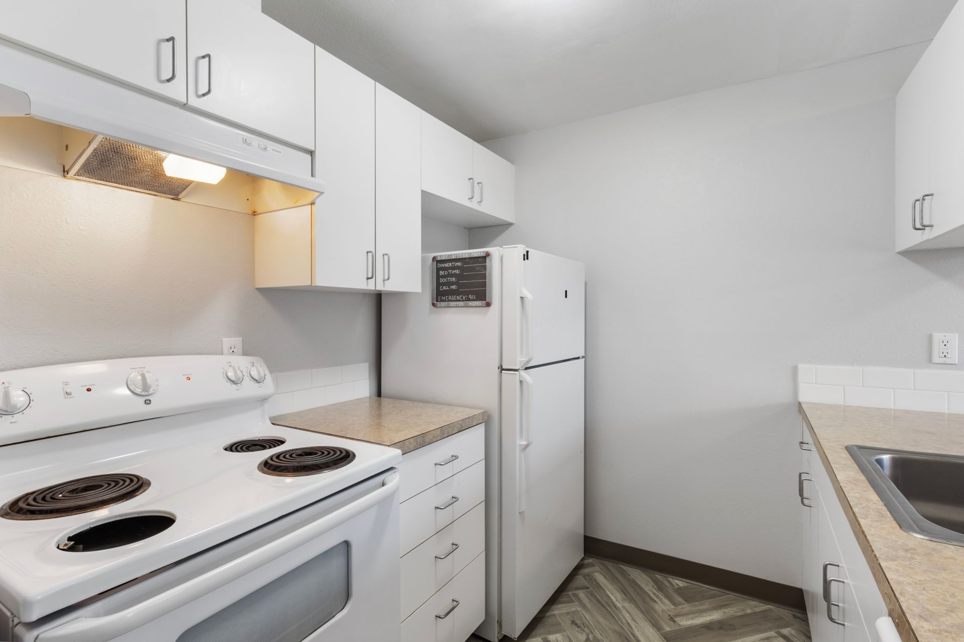A kitchen with a stove , refrigerator , sink and microwave.