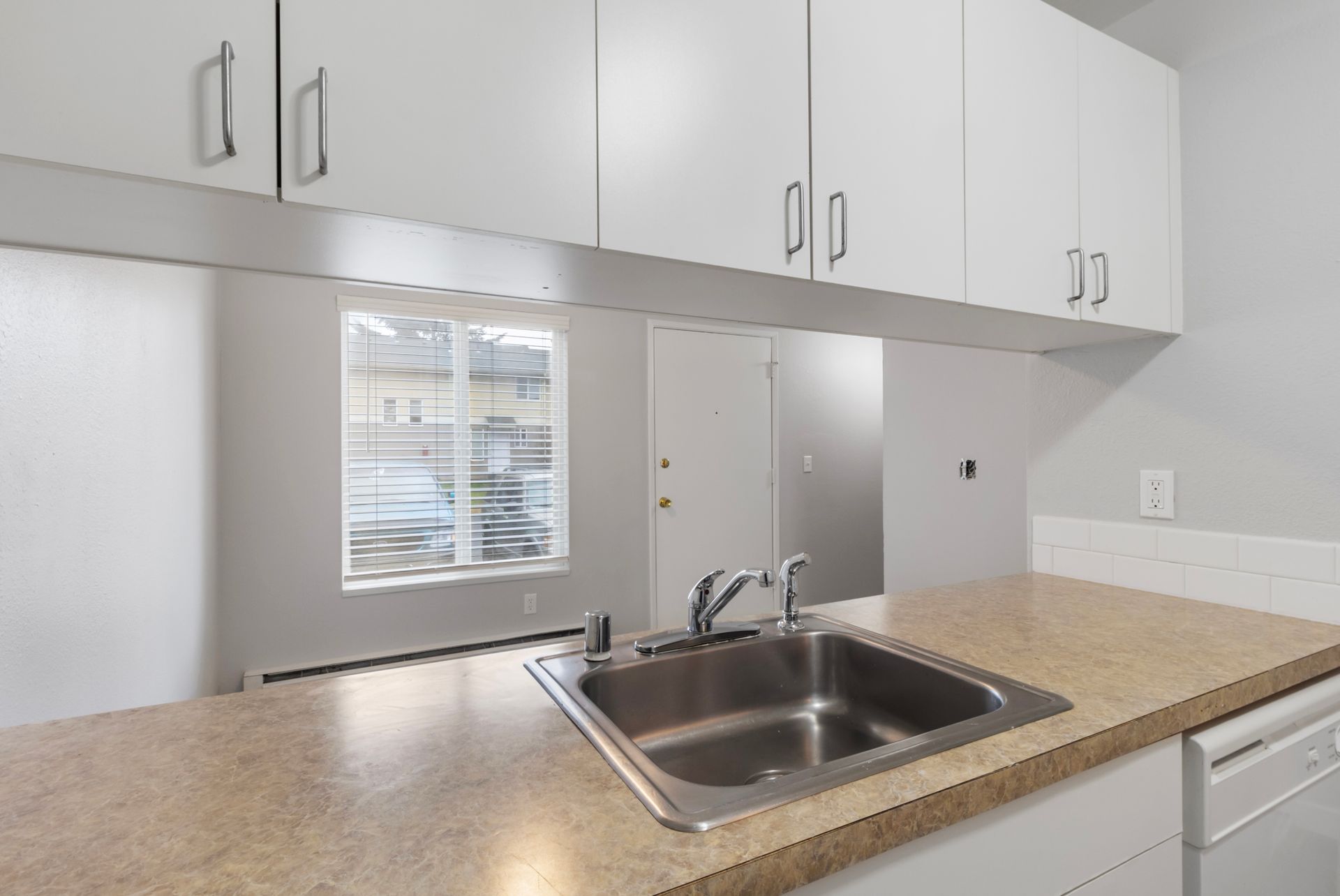 A kitchen with a stainless steel sink and white cabinets.