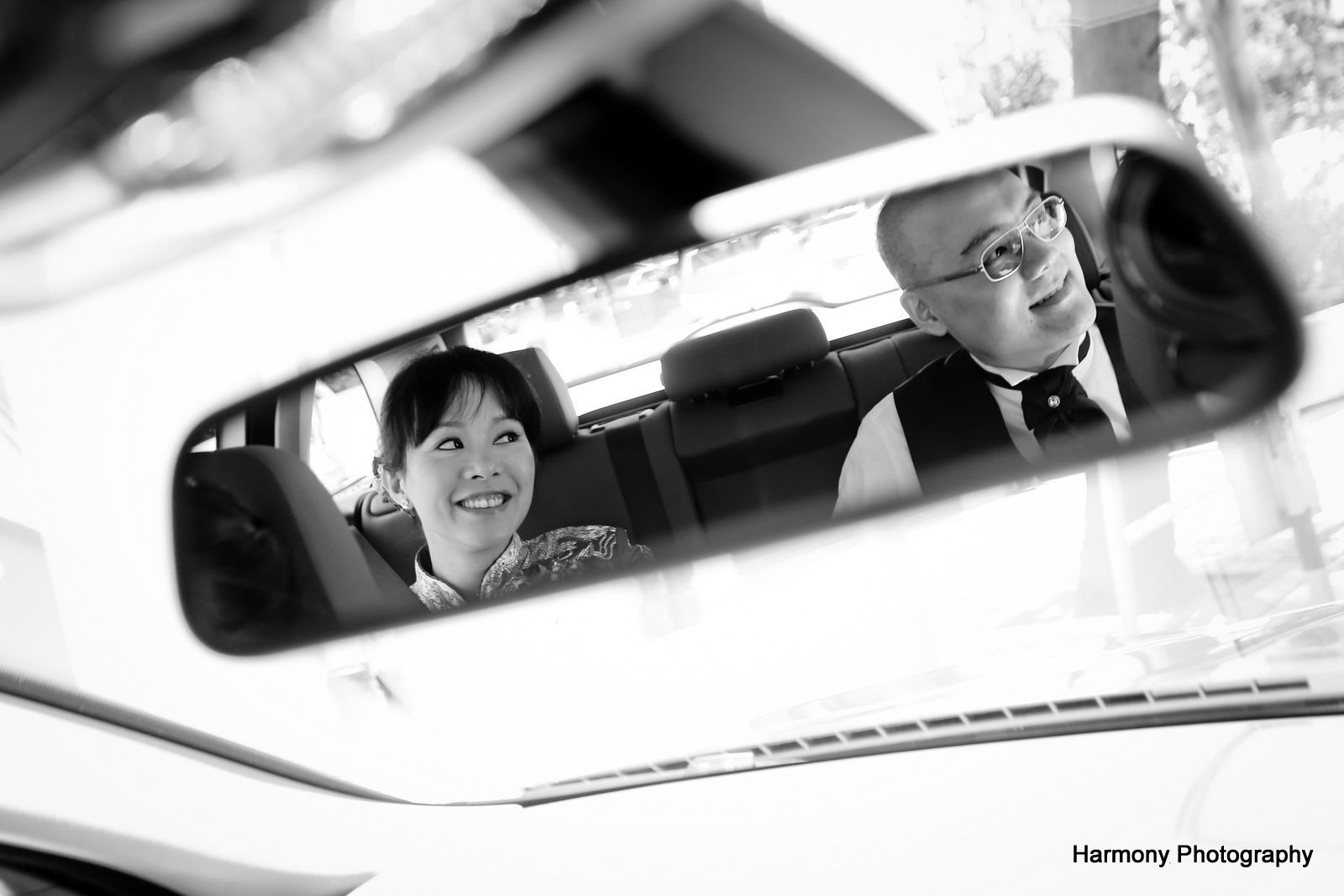 A man and a woman are reflected in the rear view mirror of a car.
