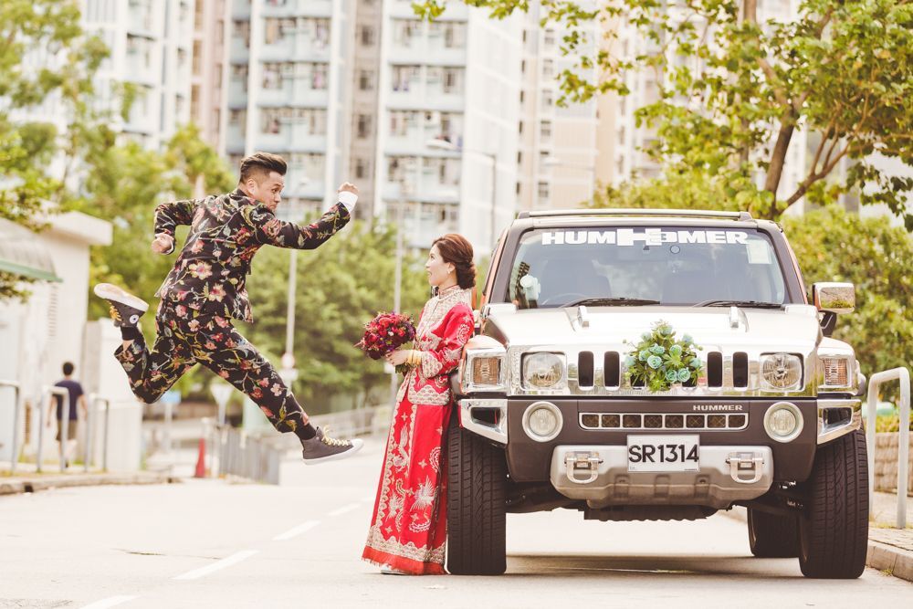 A bride and groom are posing for a picture in front of a hummer.