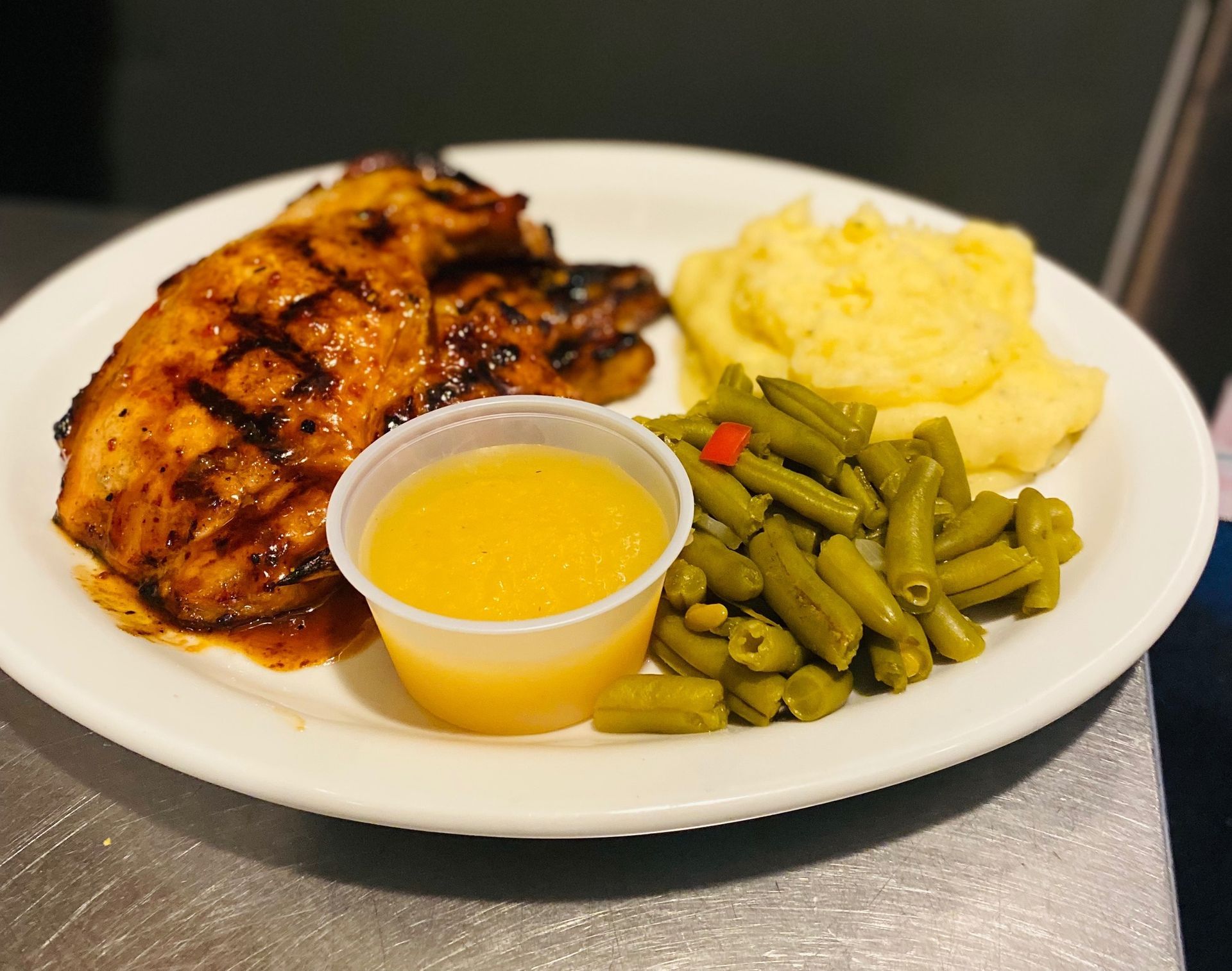 A white plate topped with chicken green beans and mashed potatoes