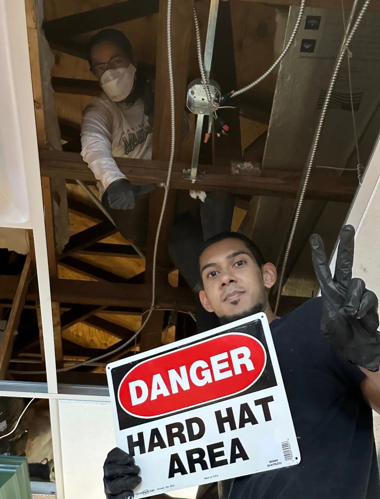 A man is holding a sign that says danger hard hat area