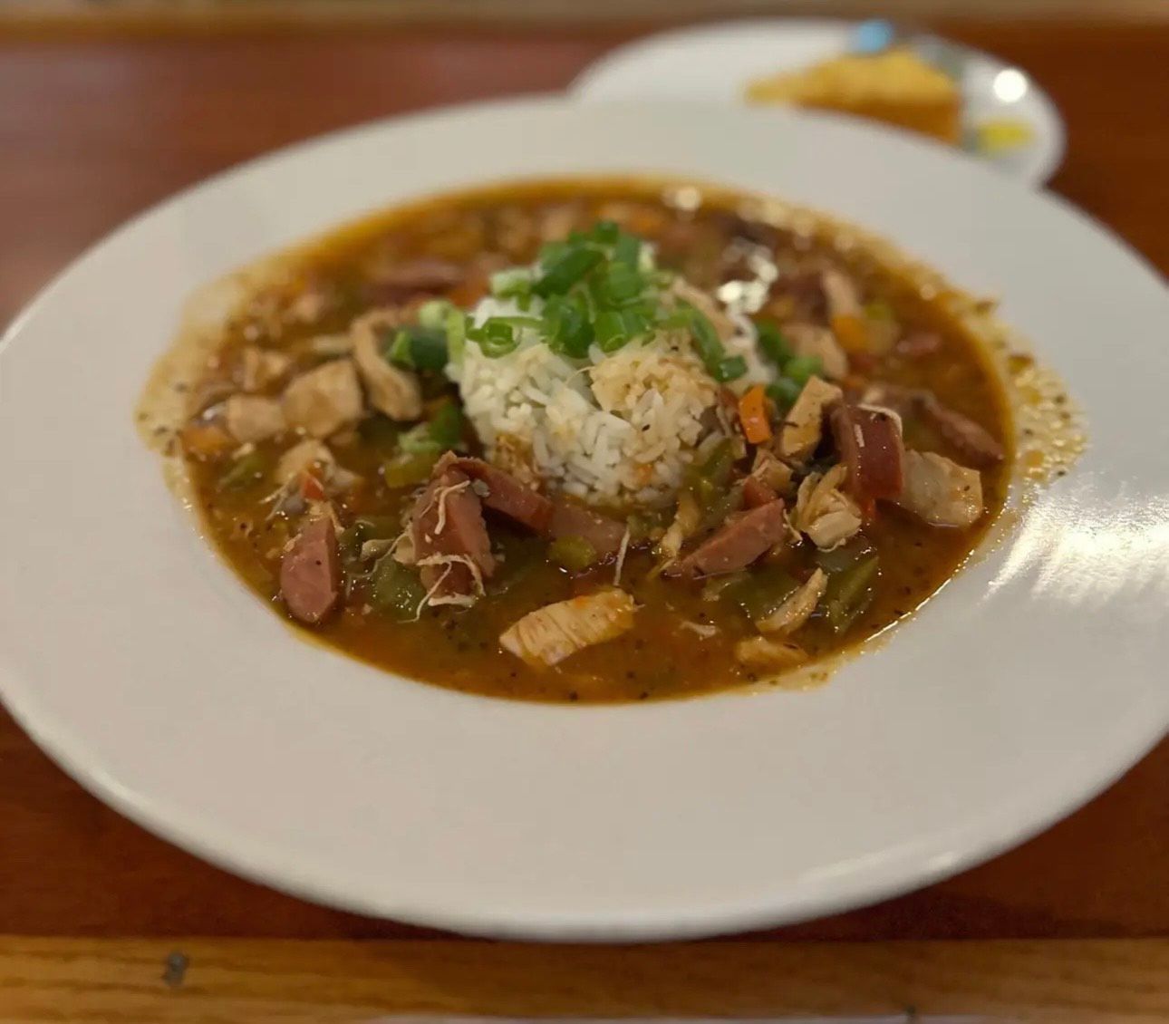 A bowl of soup with rice and meat on a table.