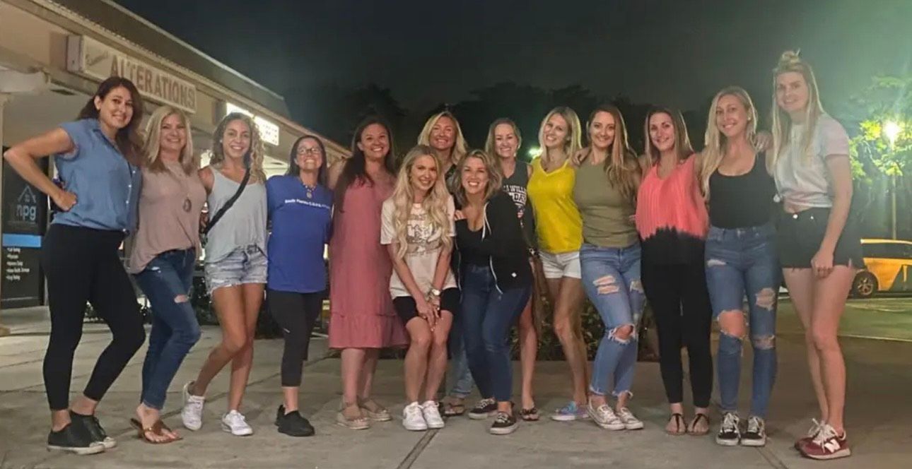 A group of women are posing for a picture together in front of a building.