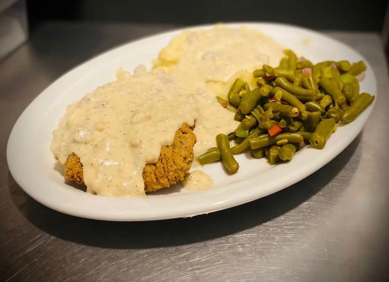 A plate of food with green beans and mashed potatoes on a table.