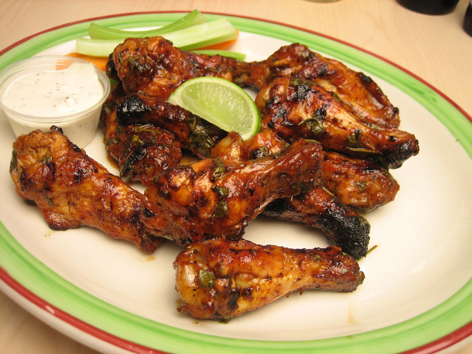 A plate of chicken wings with celery and dipping sauce