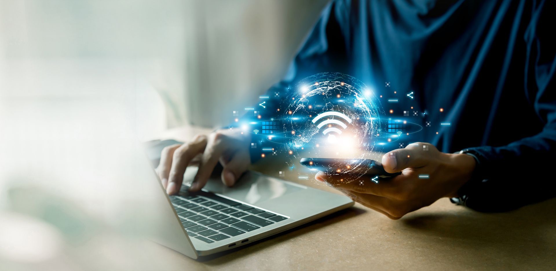 Person using a laptop and phone, with digital light effects indicating wifi connection.