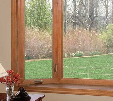 A wooden bay window looking out over a green lawn with a decorative lattice pattern on the glass.