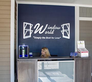 Reception desk at a Window World showroom featuring the company logo on a dark blue wall.