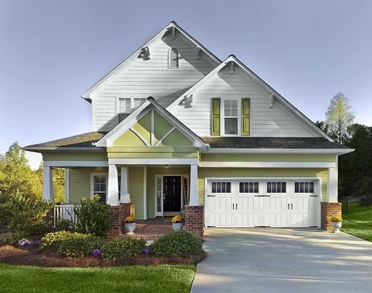 A two-story suburban house with white siding, a pale green lower level, a front porch, and a white two-car garage.