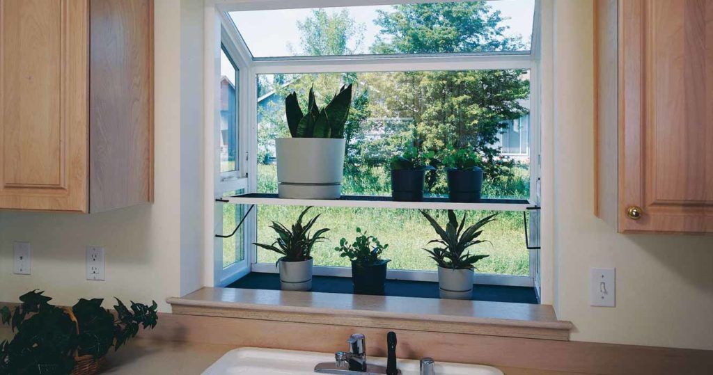 A garden window above a kitchen sink, featuring five potted plants on two shelves and natural light from outside.