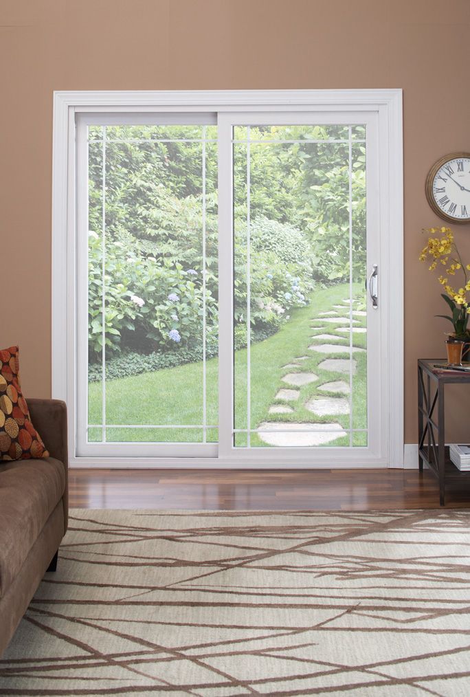 A white-framed sliding glass door with a grid pattern, looking out onto a green backyard with a stone path.
