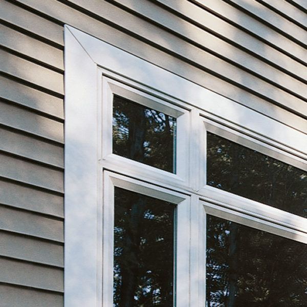 A white-framed window set into a wall with light-colored horizontal siding.