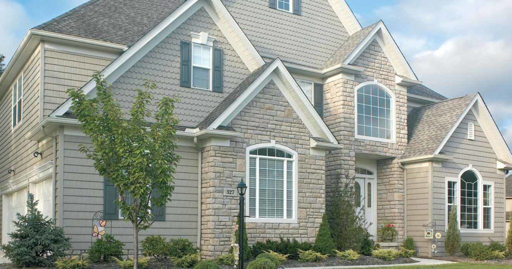 A two-story suburban house with stone and siding exterior, multiple roof gables, and a landscaped front yard.