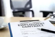 An employment contract document on a clipboard with a pen on a desk in an office setting.