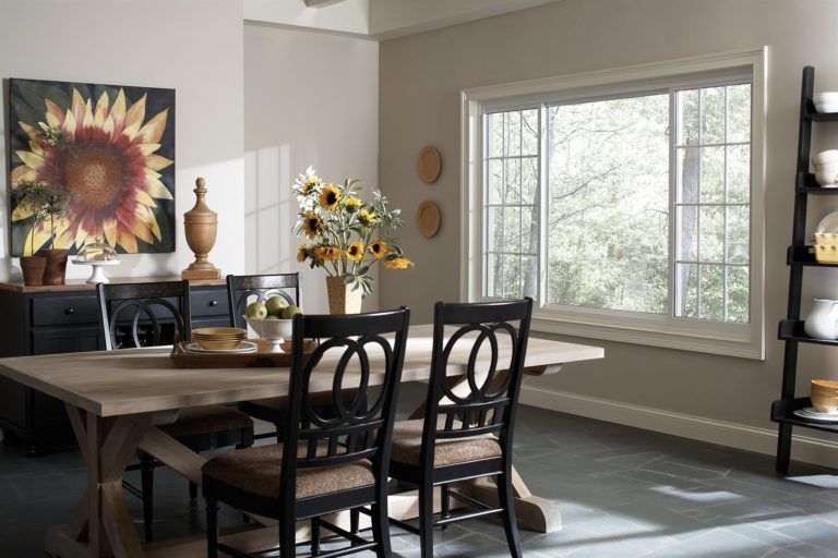 A rustic wooden dining table and black chairs set in a bright, sunlit room featuring sunflower decor and a large window.