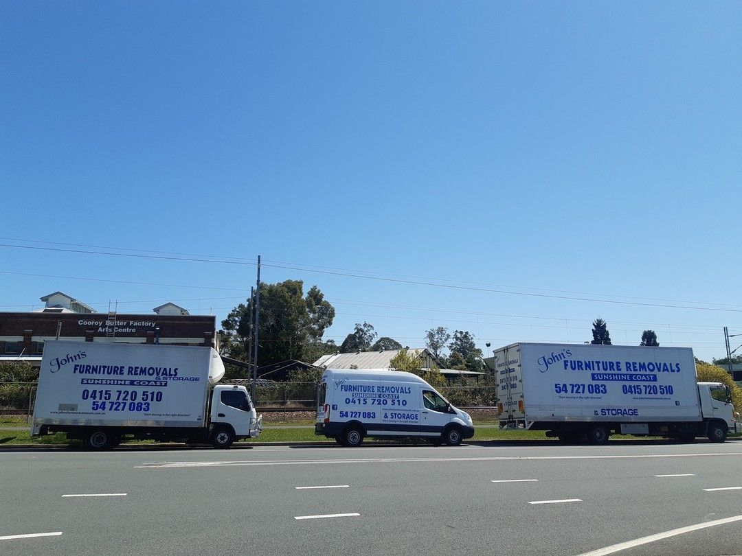 Three White Moving Trucks Parked on a Road Against a Blue Sky — John's Furniture Removals in Maryborough, QLD