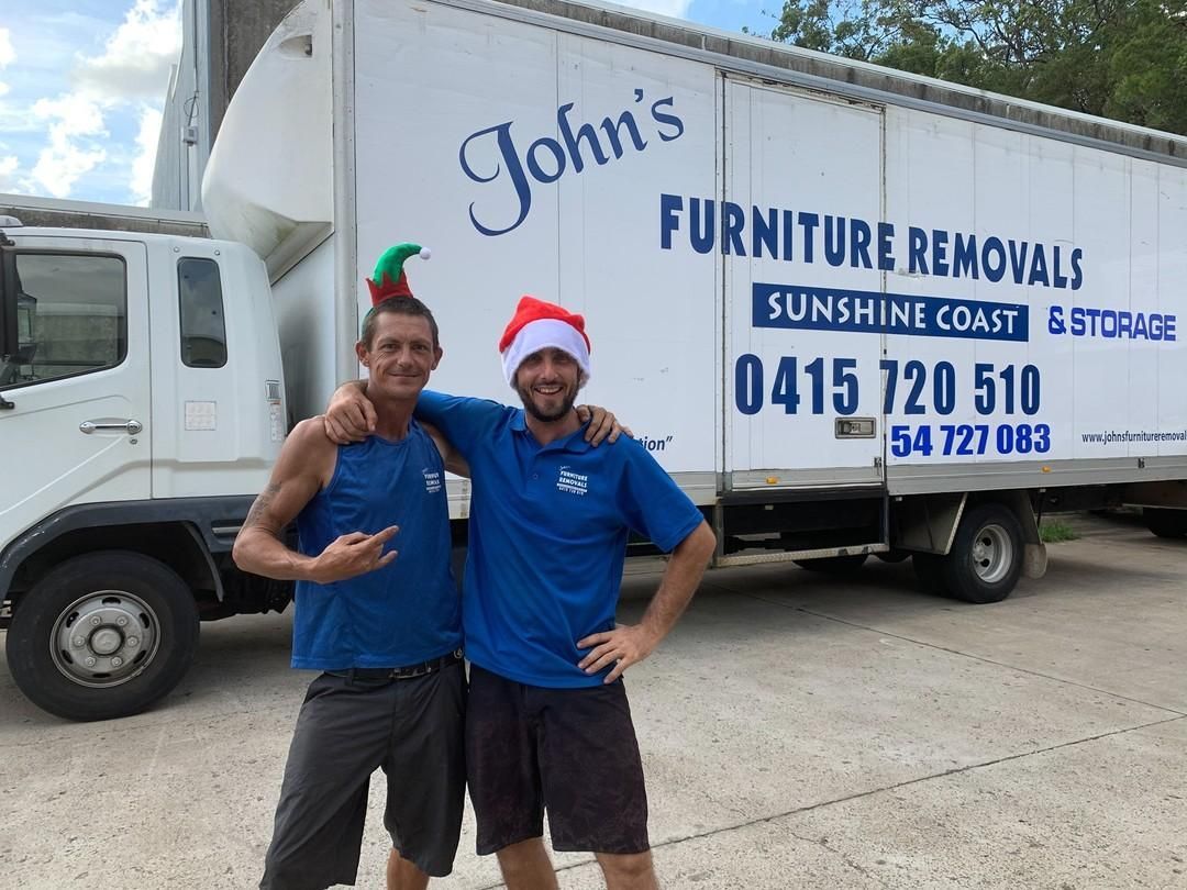 Two Men in Front of Moving Truck One in an Elf Hat, the Other a Santa Hat — John's Furniture Removals in Sunshine Coast, QLD