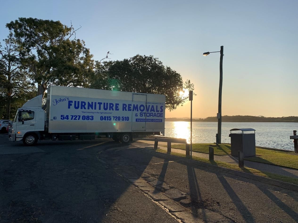White Moving Truck Parked Near a Body of Water at Sunset — John's Furniture Removals in Hervey Bay, QLD
