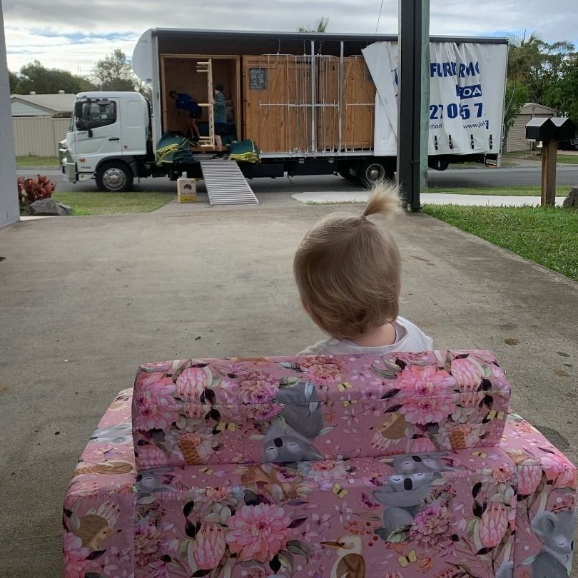 Child Sits on a Pink Floral Couch, Watching Movers Load a Truck — John's Furniture Removals in Mountain Creek, QLD