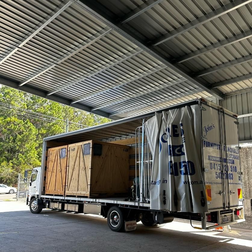 Truck Loaded With Wooden Crates Under a Metal Awning in an Outdoor Setting — John's Furniture Removals in Yandina, QLD