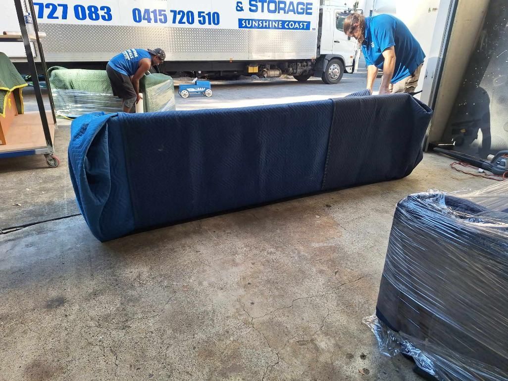 Movers Loading a Blue-covered Couch Onto a Truck at a Storage Facility — John's Furniture Removals in Nambour, QLD