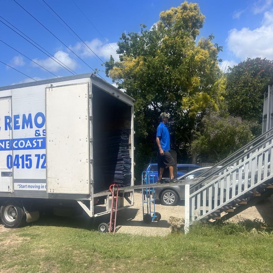 Person in Work Gloves and Overalls Packing a Cardboard Box — John's Furniture Removals in Maroochydore, QLD