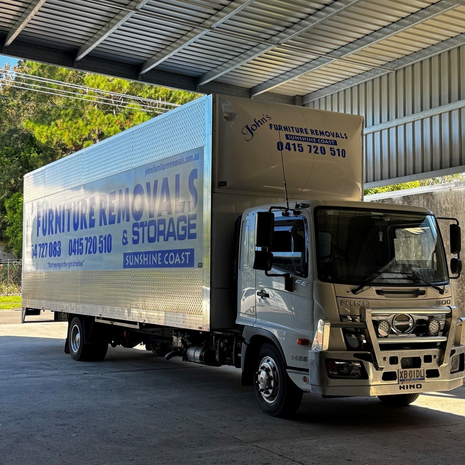 Moving Trucks Parked Under Large Shed— John's Furniture Removals in Sunshine Coast, QLD