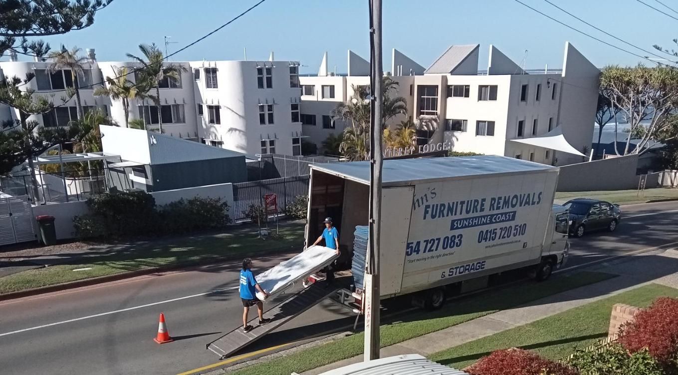 Moving Truck With Movers Loading a Large White Mattress — John's Furniture Removals in Bundaberg, QLD