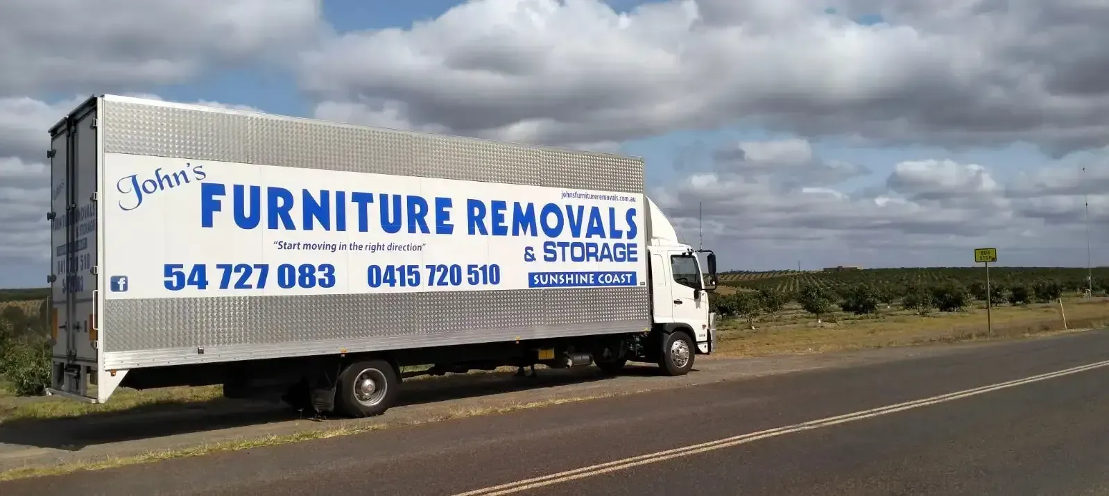 Furniture Removal Truck on a Road Under a Cloudy Sky — John's Furniture Removals in Sunshine Coast, QLD