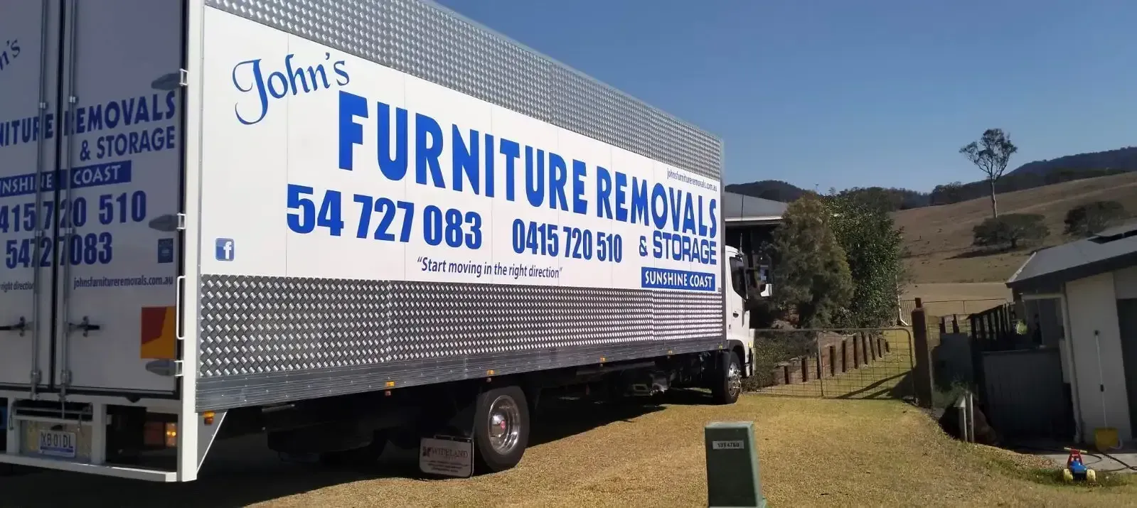 Moving Truck Parked in a Driveway Saying “John's Furniture Removals” 
— John's Furniture Removals in Sunshine Coast, QLD
