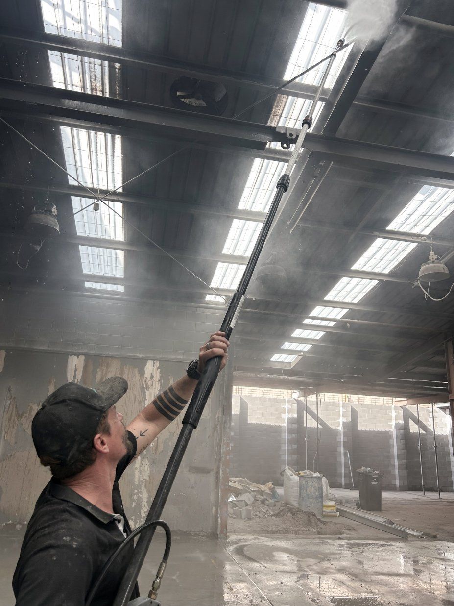 A man is cleaning the roof of a building with a high pressure washer.