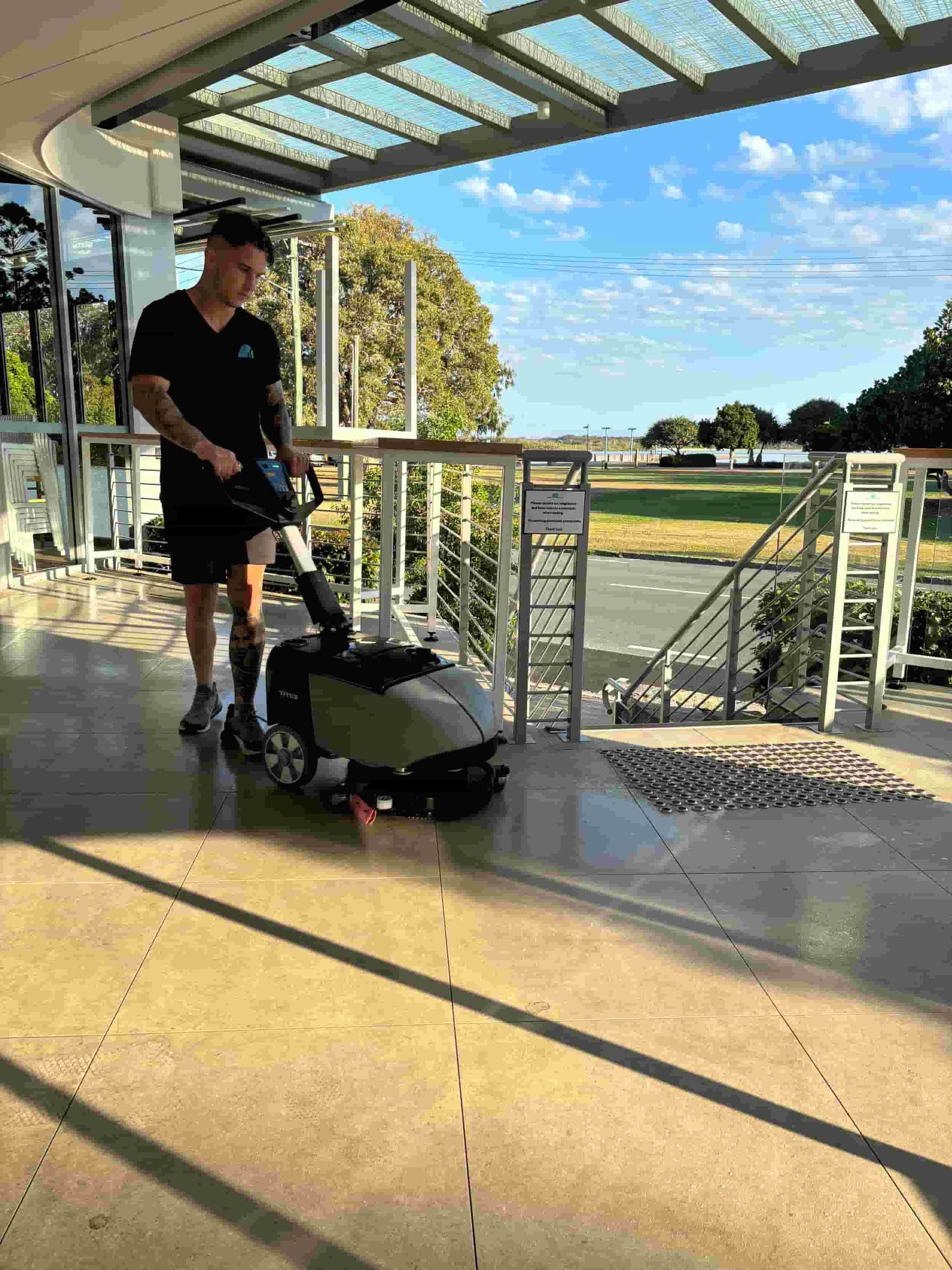 A Man is Cleaning the Floor of a Building With a Machine — Commercial Asset Maintenance In Gympie, QLD