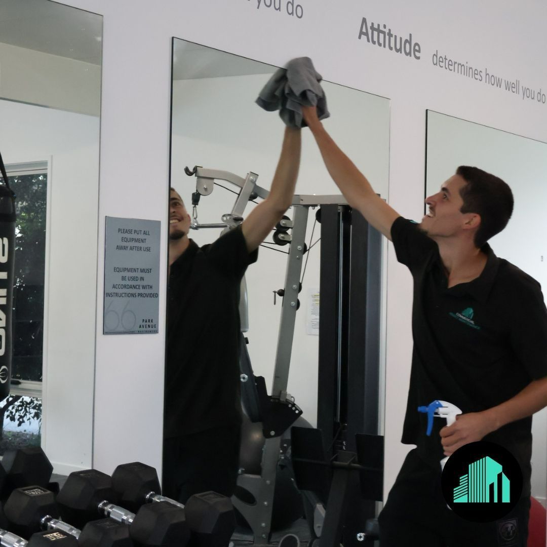 A Man Cleaning a Mirror in A Gym — Commercial Asset Maintenance In Mooloolaba, QLD