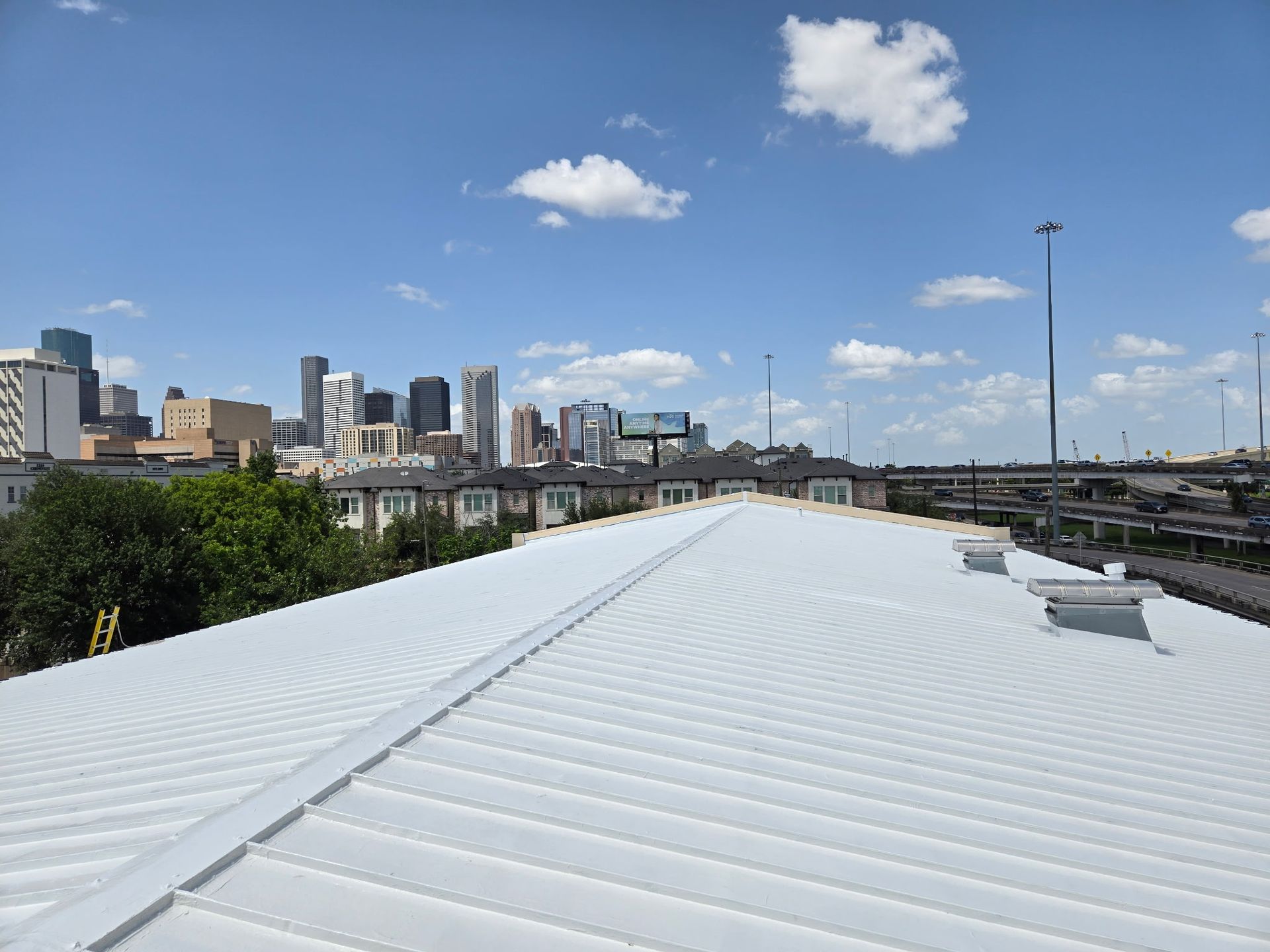 White metal roof with Denver skyline in the distance on a sunny day.