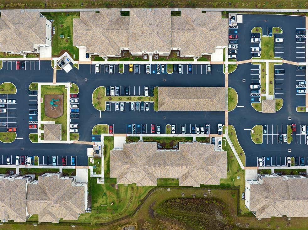 Overhead view of an apartment complex with buildings, parking areas, and a playground.