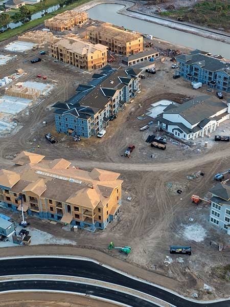 Aerial view of apartment complex construction with multiple buildings in various stages of completion.