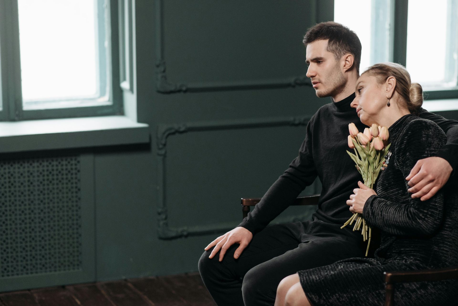 A man is sitting next to a woman holding a bouquet of flowers.