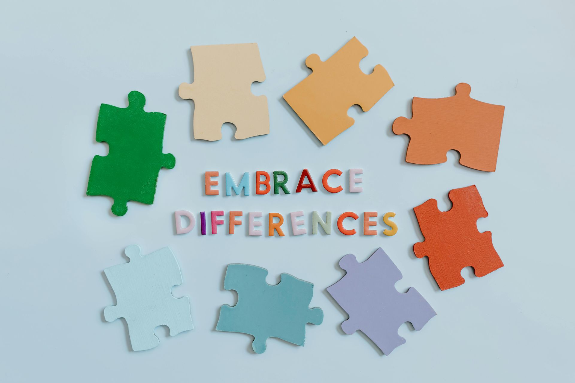 A bunch of puzzle pieces with the words `` embrace differences '' written on them.