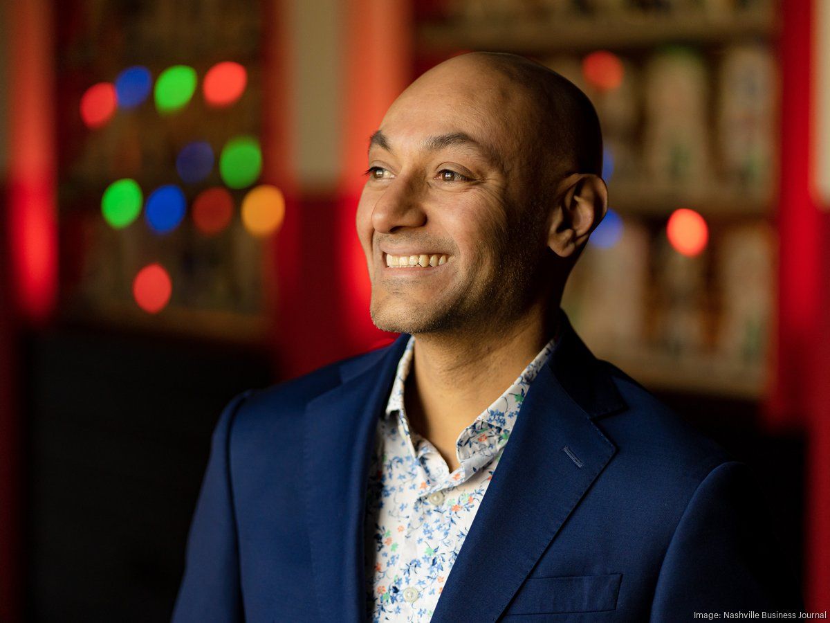 A man in a blue suit and white shirt is smiling.