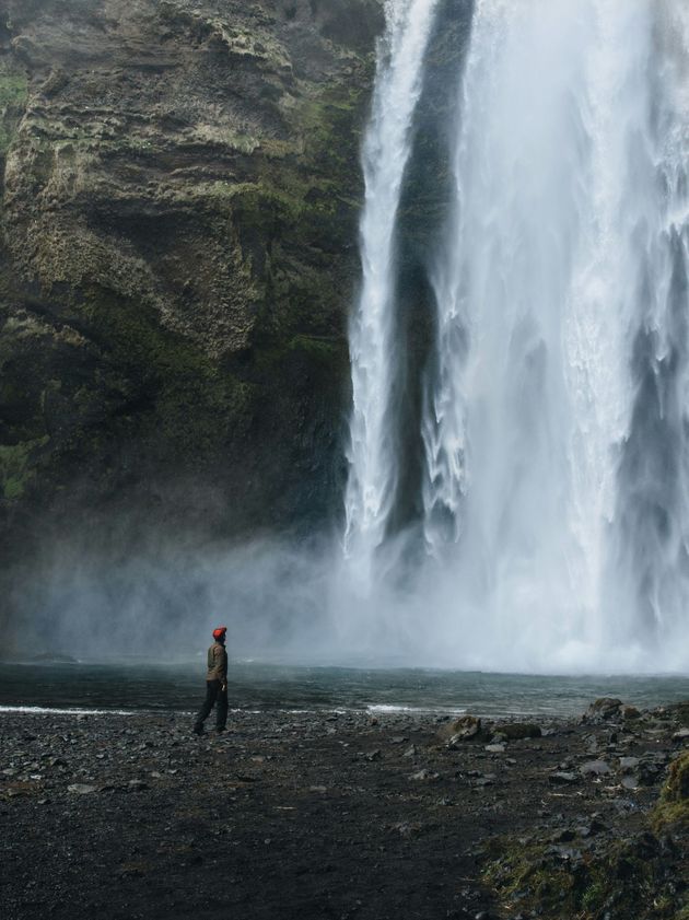 A person is standing in front of a waterfall.