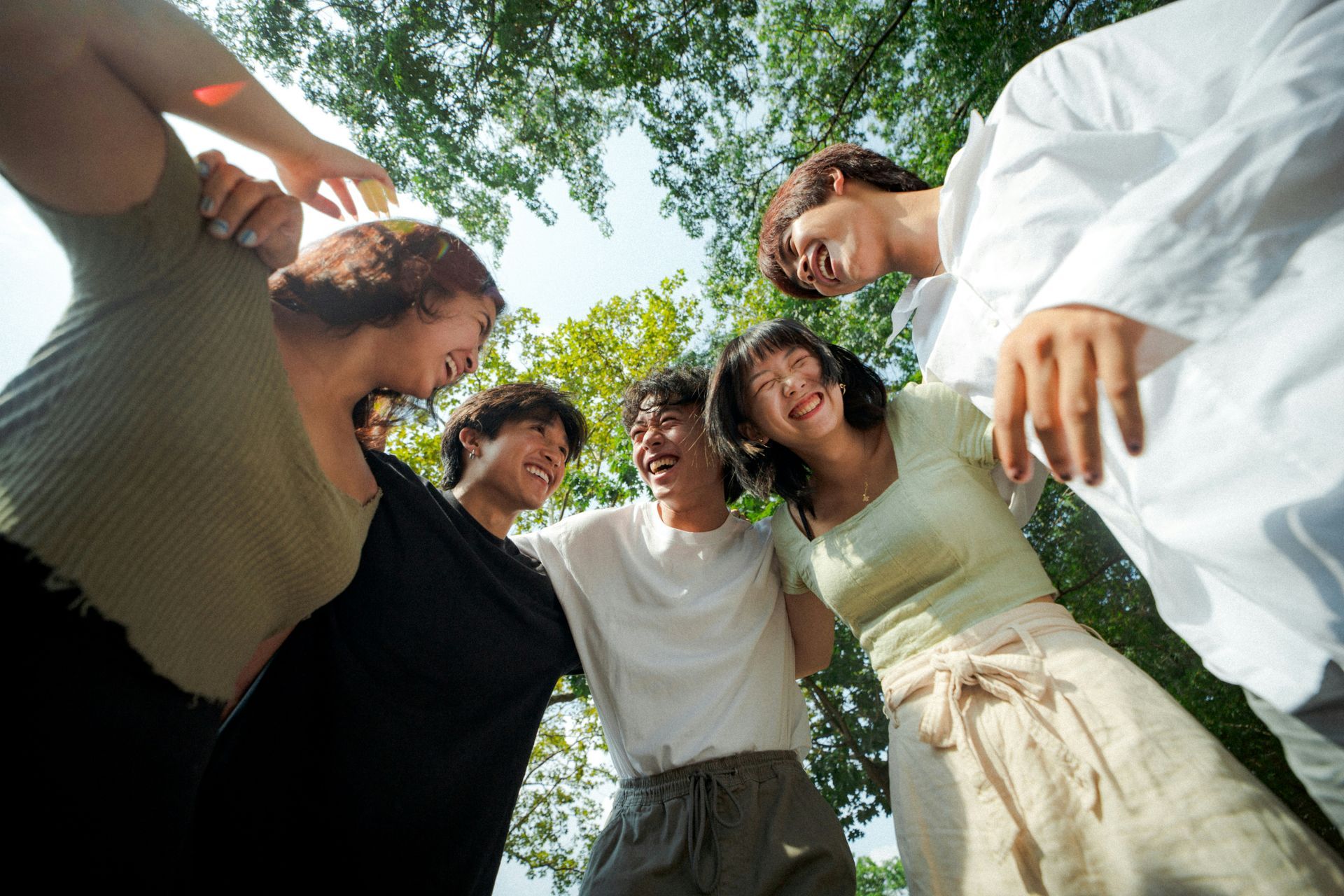 A group of people are standing in a circle with their arms around each other.