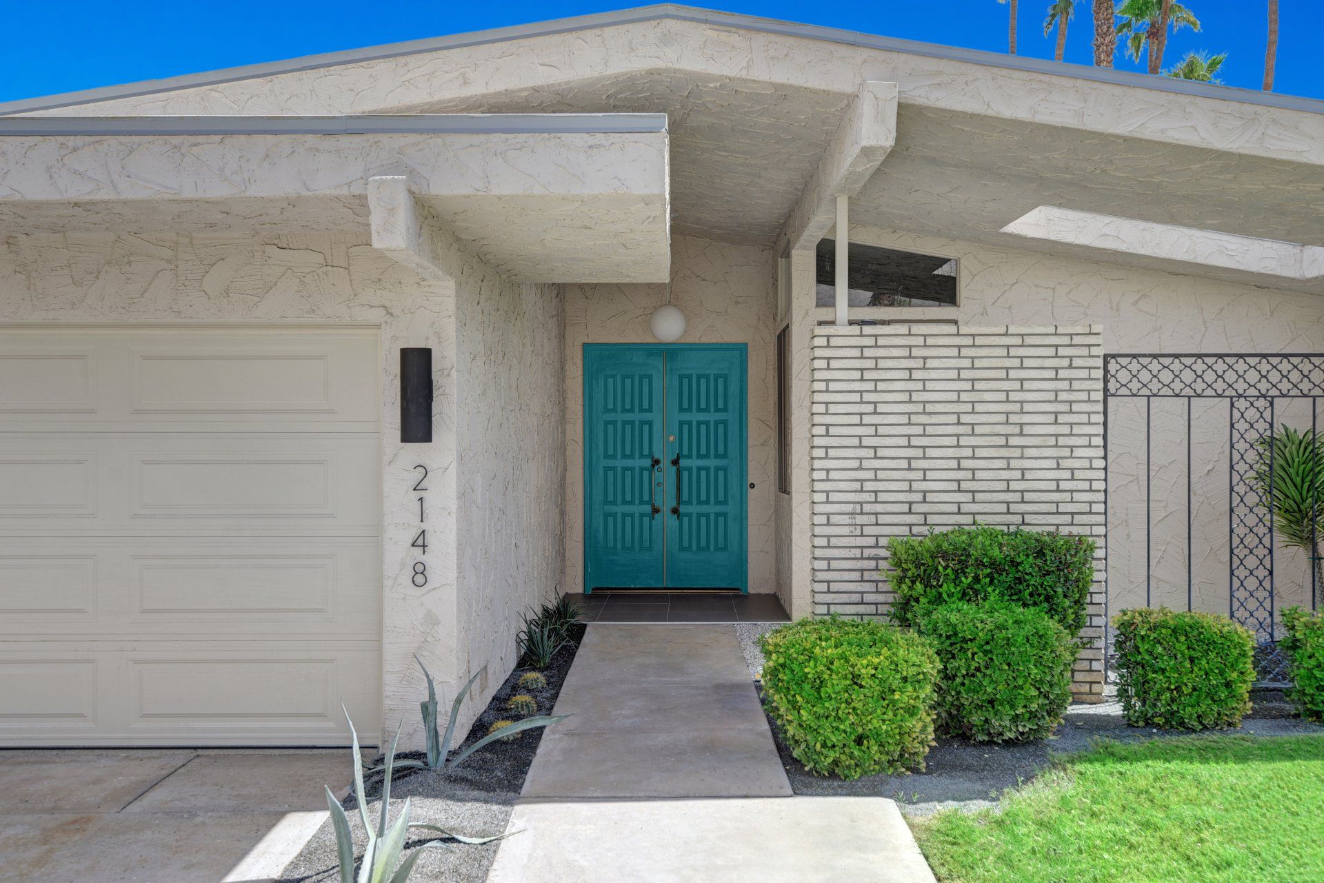 The front of a house with a blue door and a white garage door.